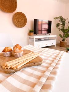 a bed with a tray with muffins and a tv at Apartamento Rincón Playa Carril in Vilagarcia de Arousa +16 photos