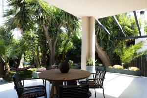 a patio with a table and chairs and palm trees at Malvina homes Karteros in Karteros