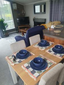 una sala de estar con una mesa con placas azules. en Primrose Valley Lakeside Lodge, en Filey 7 fotos más