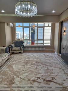 a living room with a chandelier and a large window at Квартира in Atyraū +3 photos