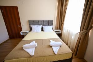 a bedroom with a bed with two white towels on it at Kristin Palace in Obzor