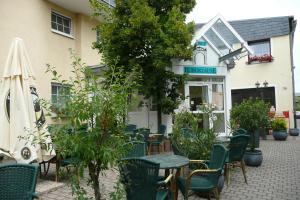 una cafetería con mesas y sillas frente a un edificio en Hotel Burgklause, en Nickenich