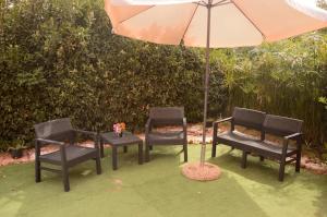 three chairs and a table with an umbrella at Spiaggia LazzarettoHouse in Alghero