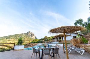 a patio with a table and chairs and an umbrella at Villa olimá in El Gastor