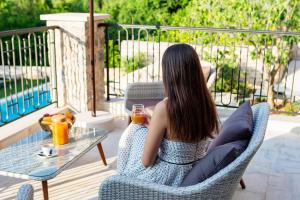 a woman sitting in a chair on a patio at Boutique hotel Ruzmarin SPA & Garden by Aycon in Budva