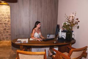 a woman sitting at a table with a computer at Boutique hotel Ruzmarin SPA & Garden by Aycon in Budva