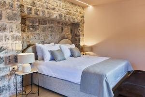 a bedroom with a bed and a brick wall at Boutique hotel Ruzmarin SPA & Garden by Aycon in Budva