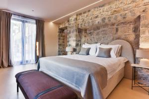 a bedroom with a large bed with a stone wall at Boutique hotel Ruzmarin SPA & Garden by Aycon in Budva