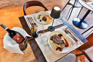 a table with two plates of food and a bottle of wine at Boutique hotel Ruzmarin SPA & Garden by Aycon in Budva