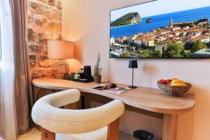 a home office with a desk and a tv on the wall at Boutique hotel Ruzmarin SPA & Garden by Aycon in Budva