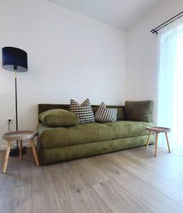 a living room with a green couch and two tables at Apartman Villeto in Stari Grad