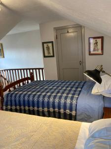 a bedroom with two beds with a blue plaid blanket at The Kennywood Suite in Duquesne