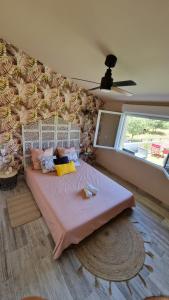 a bedroom with a large bed with pink sheets and a window at Les 3 Chênes in Puechredon