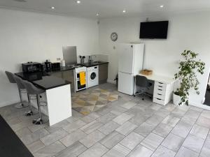 a kitchen with a refrigerator and a table and a desk at Spacious private cinema guest house in Brentwood