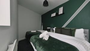 two beds in a room with green walls at Group Bookings: Up To 30 Guests Across 5 Spacious Flats! Keyless Access Free Wifi & Parking in Birmingham