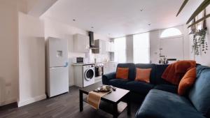 a living room with a blue couch and a kitchen at Group Bookings: Up To 30 Guests Across 5 Spacious Flats! Keyless Access Free Wifi & Parking in Birmingham