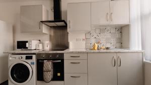 a kitchen with white cabinets and a washing machine at Group Bookings: Up To 30 Guests Across 5 Spacious Flats! Keyless Access Free Wifi & Parking in Birmingham