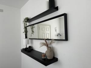 a mirror on a wall with a vase on a shelf at Group Bookings: Up To 30 Guests Across 5 Spacious Flats! Keyless Access Free Wifi & Parking in Birmingham