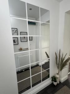 a large mirror in a white room with a plant at Group Bookings: Up To 30 Guests Across 5 Spacious Flats! Keyless Access Free Wifi & Parking in Birmingham