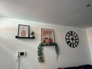 a white wall with two pictures and a clock at Group Bookings: Up To 30 Guests Across 5 Spacious Flats! Keyless Access Free Wifi & Parking in Birmingham