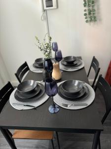 a black table with black plates and wine glasses at Group Bookings: Up To 30 Guests Across 5 Spacious Flats! Keyless Access Free Wifi & Parking in Birmingham