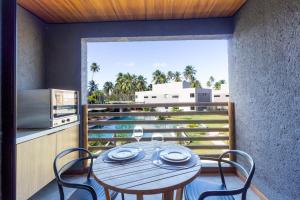 a table and chairs on a balcony with a view of the ocean at Villas Manatee Milagres por Quarto à Vista in Pôrto de Pedras