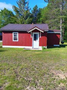 a red shed with a white door in a yard at cabin 1 in Manistique
