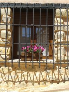 una ventana con una valla de hierro y flores rosas. en Apartamentos Turísticos Pepe en Gea de Albarracín