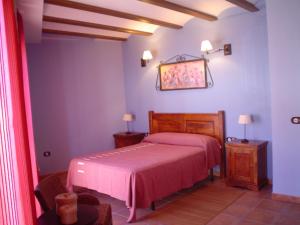 1 dormitorio con 1 cama con colcha rosa en Apartamentos Turísticos Pepe, en Gea de Albarracín