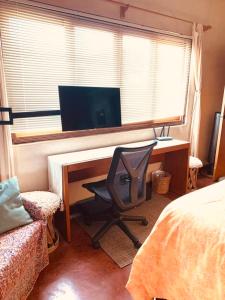 1 dormitorio con escritorio, ordenador y silla en The Cozy Nest, en Todos Santos
