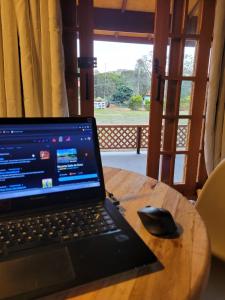 a laptop computer sitting on top of a wooden table at Chalé Rústico Moderno no Cantagalo in São Bento do Sapucaí