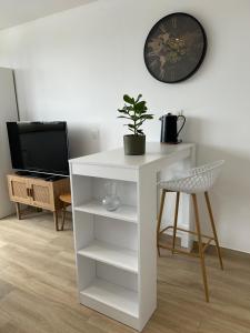 a white table with a plant and a clock on a wall at Studio Siana in Chartres