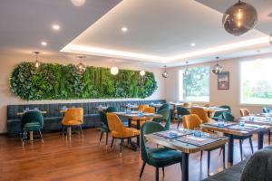 a restaurant with tables and chairs and a green wall at Golden Tulip Dieppe Hôtel & Spa in Saint-Aubin-sur-Scie