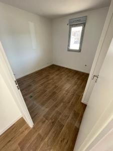 an empty room with a window and wooden floors at T2 neuf proche ocean in Messanges