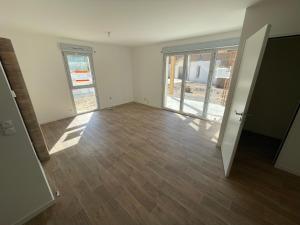 an empty room with wooden floors and windows at T2 neuf proche ocean in Messanges