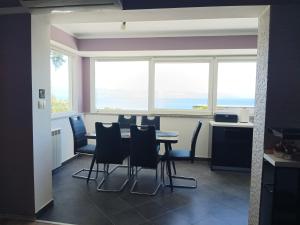 a dining room with a table and chairs and windows at Apartment D&J 2 in Mošćenička Draga +23 photos