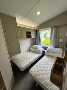 a small room with two beds and a window at Presthaven Resort 3 Bedroom Luxury Gold 2024 Caravan in Talacre +15 photos