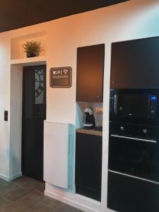 a kitchen with a white refrigerator and a black cabinet at La Loge in Sinceny