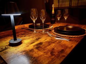 a wooden table with wine glasses and a lamp at La Loge in Sinceny