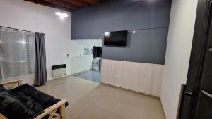 Una sala de estar con un sofá y un televisor en una pared. en Lo de Juancito, en Cipolletti