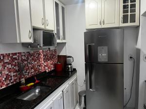 een keuken met een roestvrijstalen koelkast en witte kasten bij Apartamento Duplex Cobertura 5 min do centro in Juiz de Fora +10 foto's