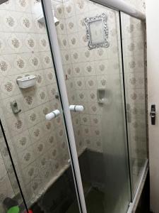 een douche met een glazen deur en een klok aan de muur bij Apartamento Duplex Cobertura 5 min do centro in Juiz de Fora