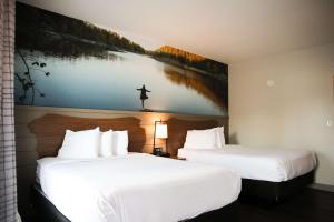 two beds in a hotel room with a painting on the wall at The Inn At Tree City, BW Signature Collection in McMinnville