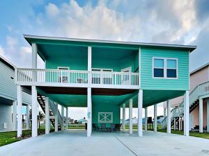 a blue house with a balcony on a driveway at Redfish Reef Retreat in Rockport