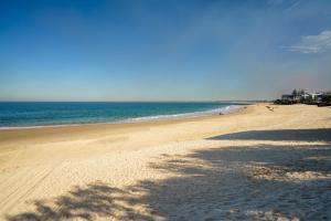 a beach with a shadow of a tree on the sand at Ocean Breeze Retreat: Kings Coastal Apartment in Caloundra
