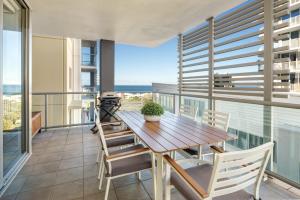 a dining room with a table and chairs on a balcony at Ocean Breeze Retreat: Kings Coastal Apartment in Caloundra