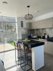 a kitchen with a black counter and some chairs at Casa Tres Ventanas de Azpitia in Santa Cruz de Flores
