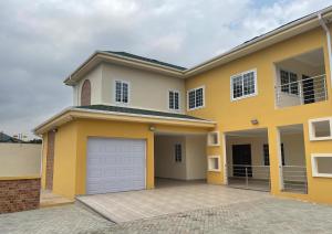 a large yellow house with a garage at Summit Residence in Accra