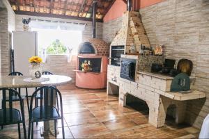 a kitchen with a brick oven and a table with chairs at Casa para temporada, represa Bortolan Poços de Caldas in Poços de Caldas