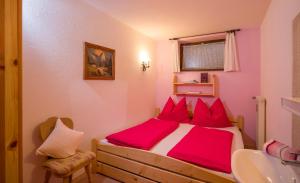 1 dormitorio con cama con almohadas rojas y lavamanos en Haus Gabriele Appartement Frederic by NV-Appartements, en Kirchberg in Tirol 2 fotos más